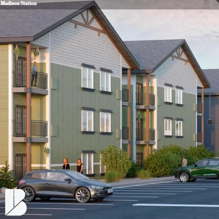 A modern three-story apartment building with green siding and balconies, Madison Station Rexburg features several people on balconies and near the entrance. Two cars are parked in front, and the image displays "Madison Station" at the top.
