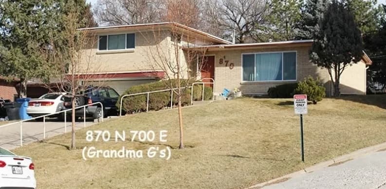 A beige, split-level house on Austin Ridge with address 870 shown, a sloped front yard, leafless trees, and two cars in the driveway. Text reads 870 N 700 E (Grandma G's), Logan. A small sign sits by the curb.