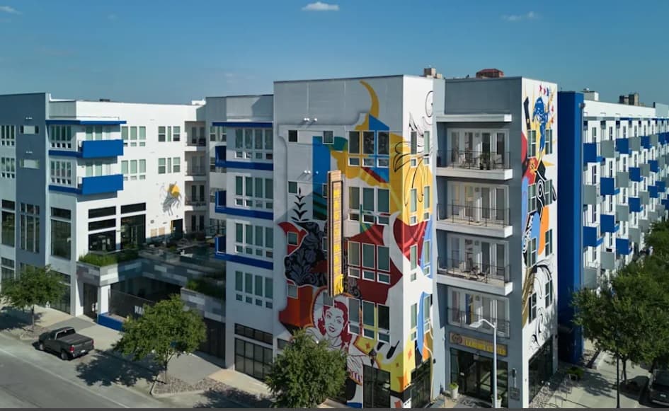 A multistory building with colorful artwork on the side stands out in Mag & May Fort Worth.