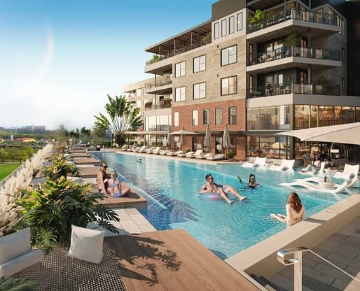 Modern apartment complex The Lofts at West 7th Fort Worth features balconies overlooking a stylish outdoor pool. People are swimming, relaxing on lounge chairs, and socializing by the water. Lush plants line the poolside under a clear, sunny sky.