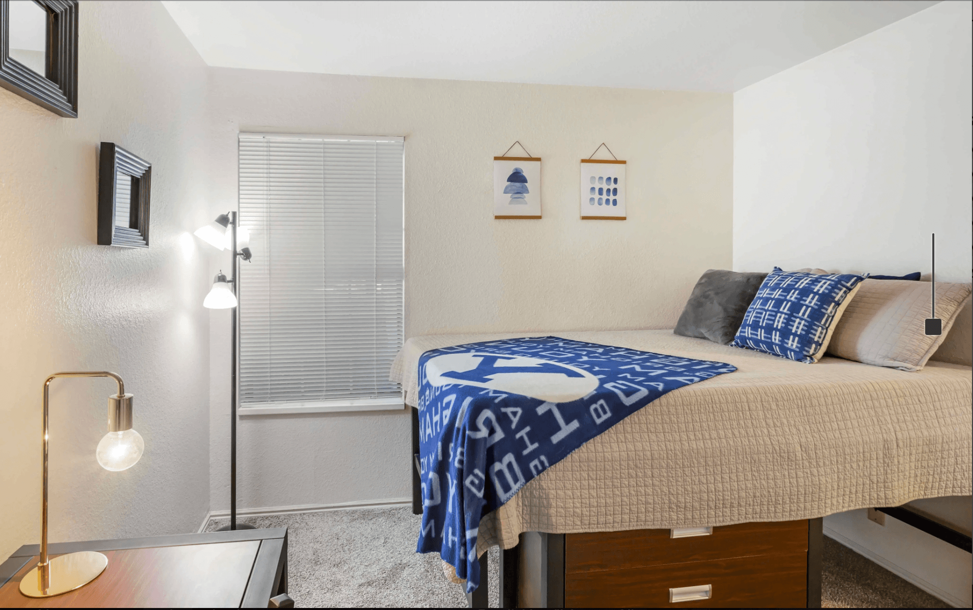 The Branbury Provo offers a two-story apartment building with brown and beige siding, outdoor staircases, and balconies. Several cars are parked in the lot under a clear blue sky.