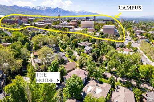 Aerial view of a suburban neighborhood with trees and houses in Salt Lake City. A yellow arrow highlights “CAMPUS” in the distance, while “THE HOUSE”—the Utah Prairie House—is marked in the foreground, set against mountain backdrops.