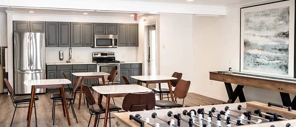 A modern Crestwood Provo break room with gray cabinets, stainless steel appliances, tables and chairs, a foosball table, a shuffleboard table, and a large abstract painting on the wall.