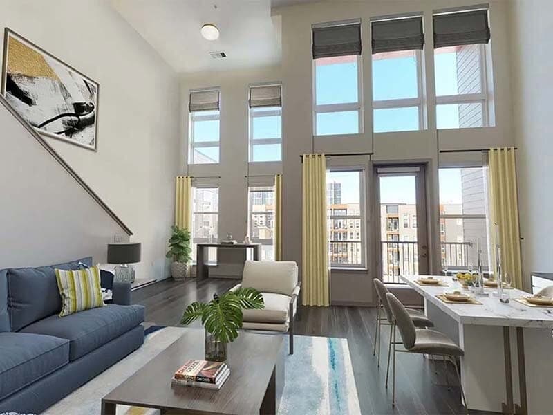 Spacious modern living room with high ceilings, large windows, contemporary furniture, a blue sofa, dining table set for six, indoor plants, and sunlight streaming in—overlooking the serene Viceroy Observatory Park.