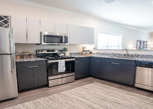 Modern kitchen in Retreat at Pullman student housing features stainless steel appliances, a two-toned cabinet design, granite countertops, and a window above the sink—perfect for residents of Pullman apartments.