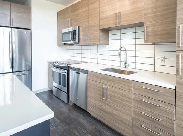 Modern kitchen with stainless steel appliances, including a refrigerator, oven, microwave, and dishwasher. Light wood cabinets and white countertops add charm. Located near Viceroy Observatory Park, this home offers both style and convenience.
