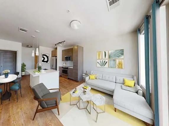 Modern open-concept living space with wood flooring, a gray sectional sofa, stylish chairs, and small marble tables. Large windows overlook Viceroy Observatory Park; contemporary decor, wall art, and a kitchen area complete the inviting room.