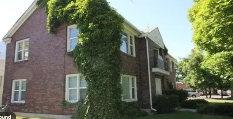 A two-story brick apartment building at 290 N 600 E Provo, with ivy climbing the center, multiple windows, and a lawn with trees on a sunny day.
