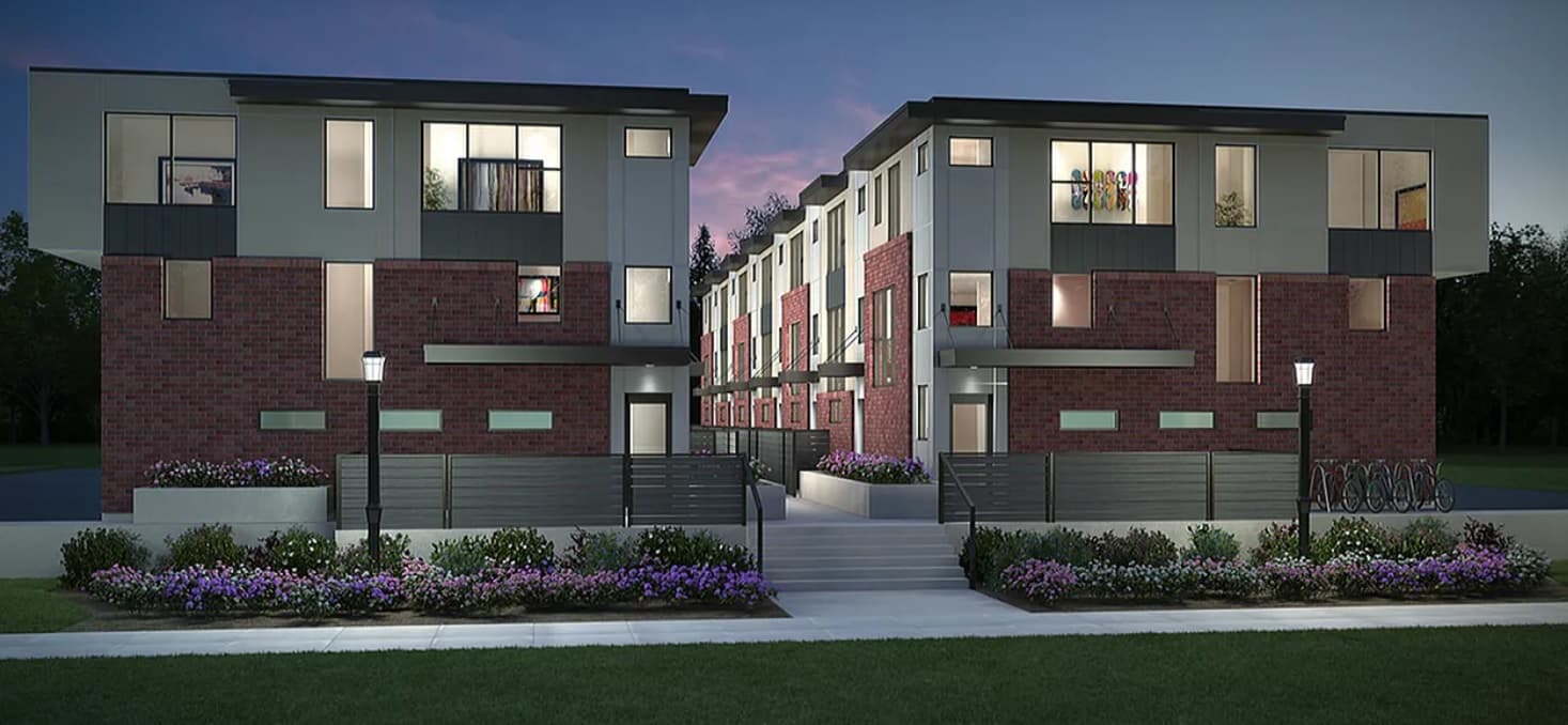 Modern three-story Sego Townhomes with brick and gray siding, large windows, outdoor lighting, landscaped flowers, and a central walkway at dusk.