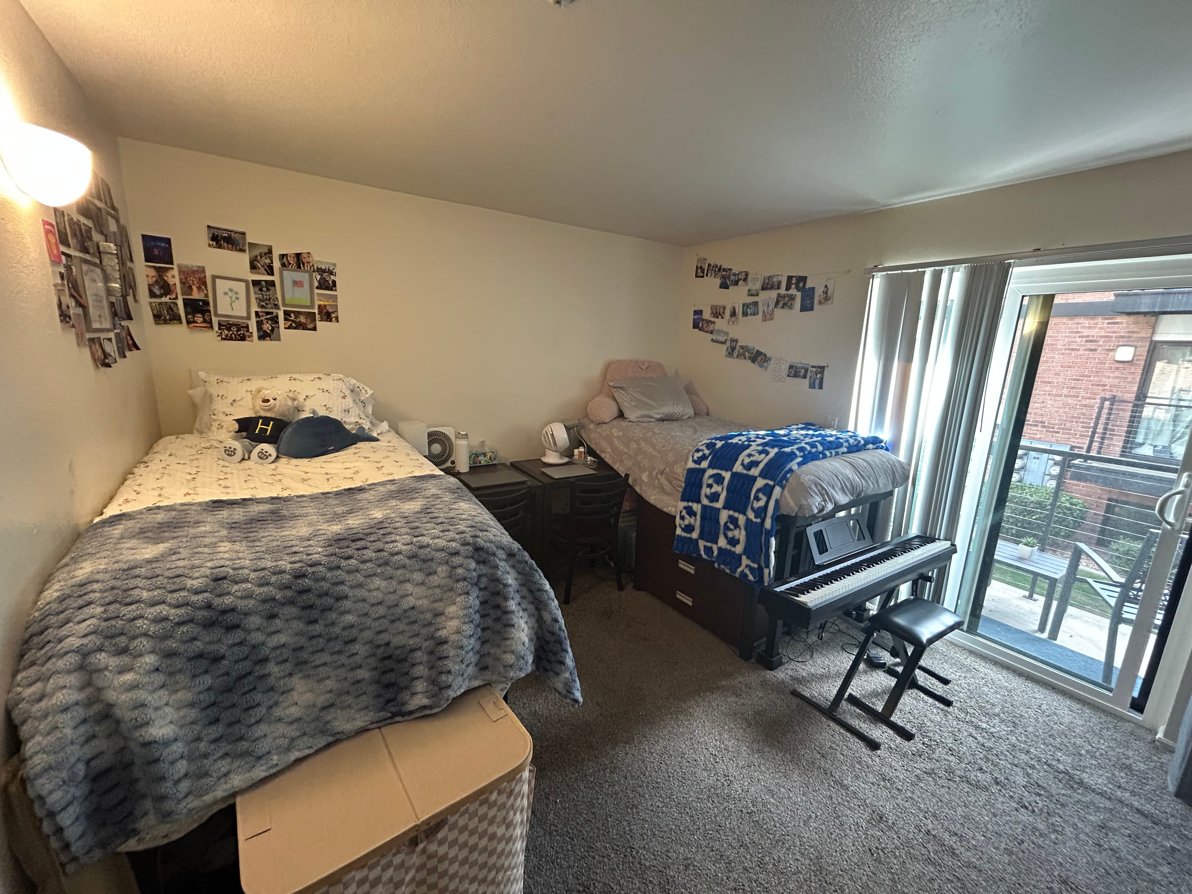 The Branbury Provo offers a two-story apartment building with brown and beige siding, outdoor staircases, and balconies. Several cars are parked in the lot under a clear blue sky.